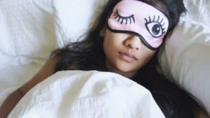 Woman wearing eye mask sleeping with one eye open