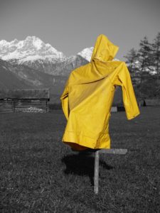 Yellow rain coat in front of snow covered mountain